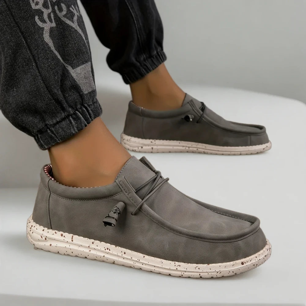 Mocassin d'été gris perle posé sur surface claire, style décontracté