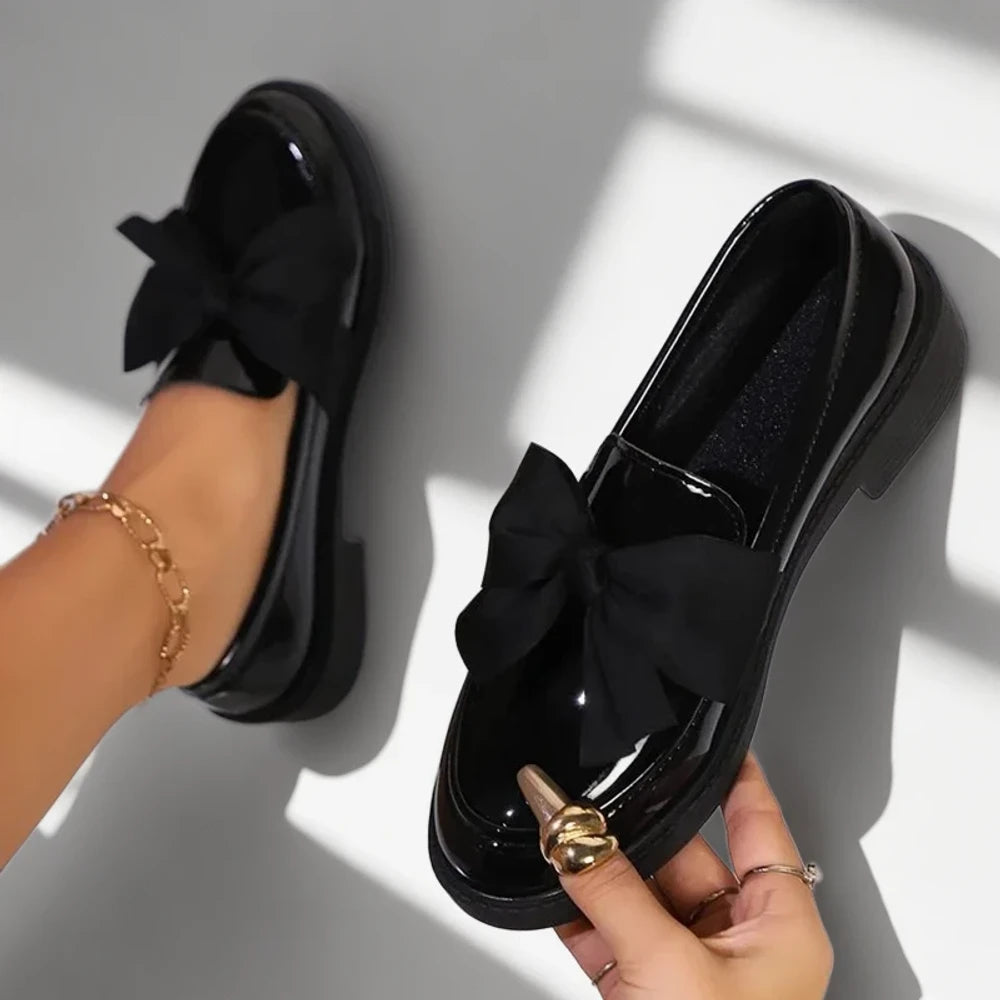 Détail gros plan mocassin femme verni noir texture plissée raffinée