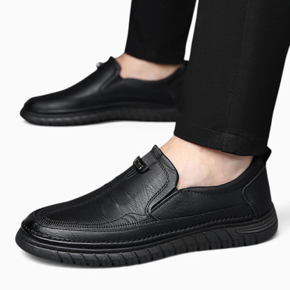 Paire de mocassins en croûte de cuir noire avec semelle crantée, portés avec un pantalon noir