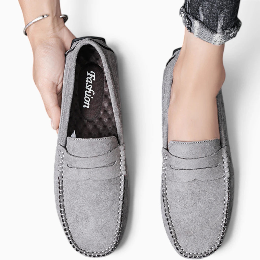 Mocassin daim gris homme porté, coutures apparentes et semelle visible